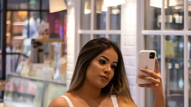 Frau in weißem Top macht ein Selfie mit dem Smartphone – Camsex Tipps