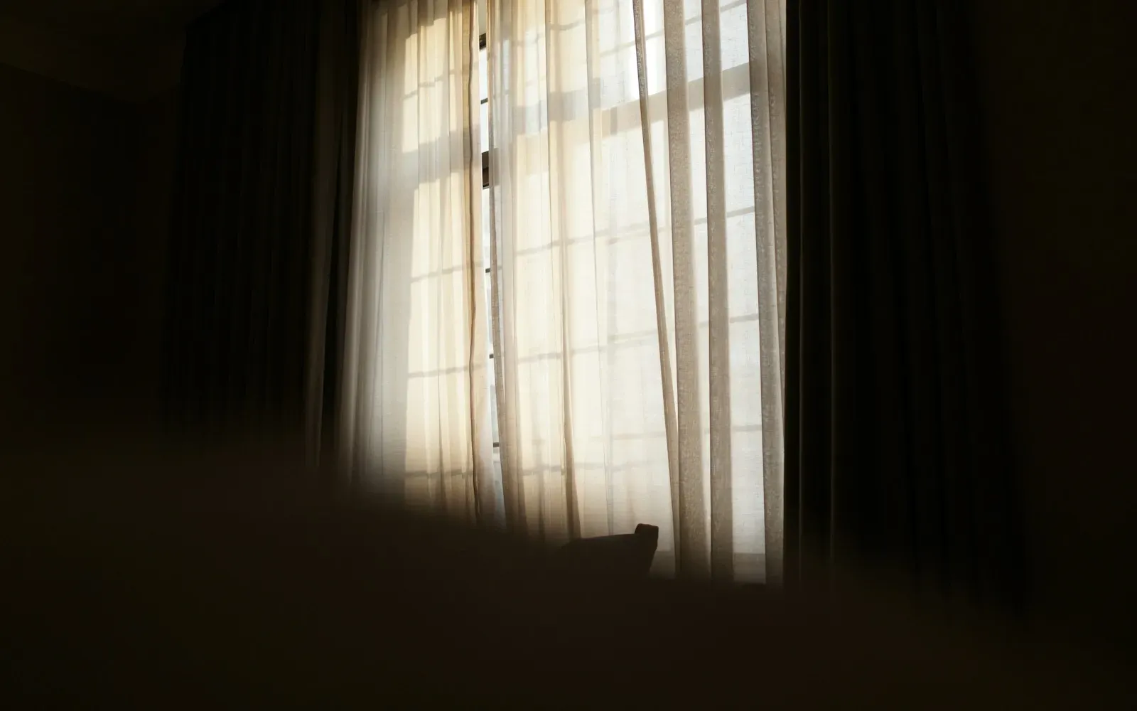 Weiches Tageslicht fällt durch helle Vorhänge in einen dunklen Raum – Webcam Beleuchtung beim Camsex