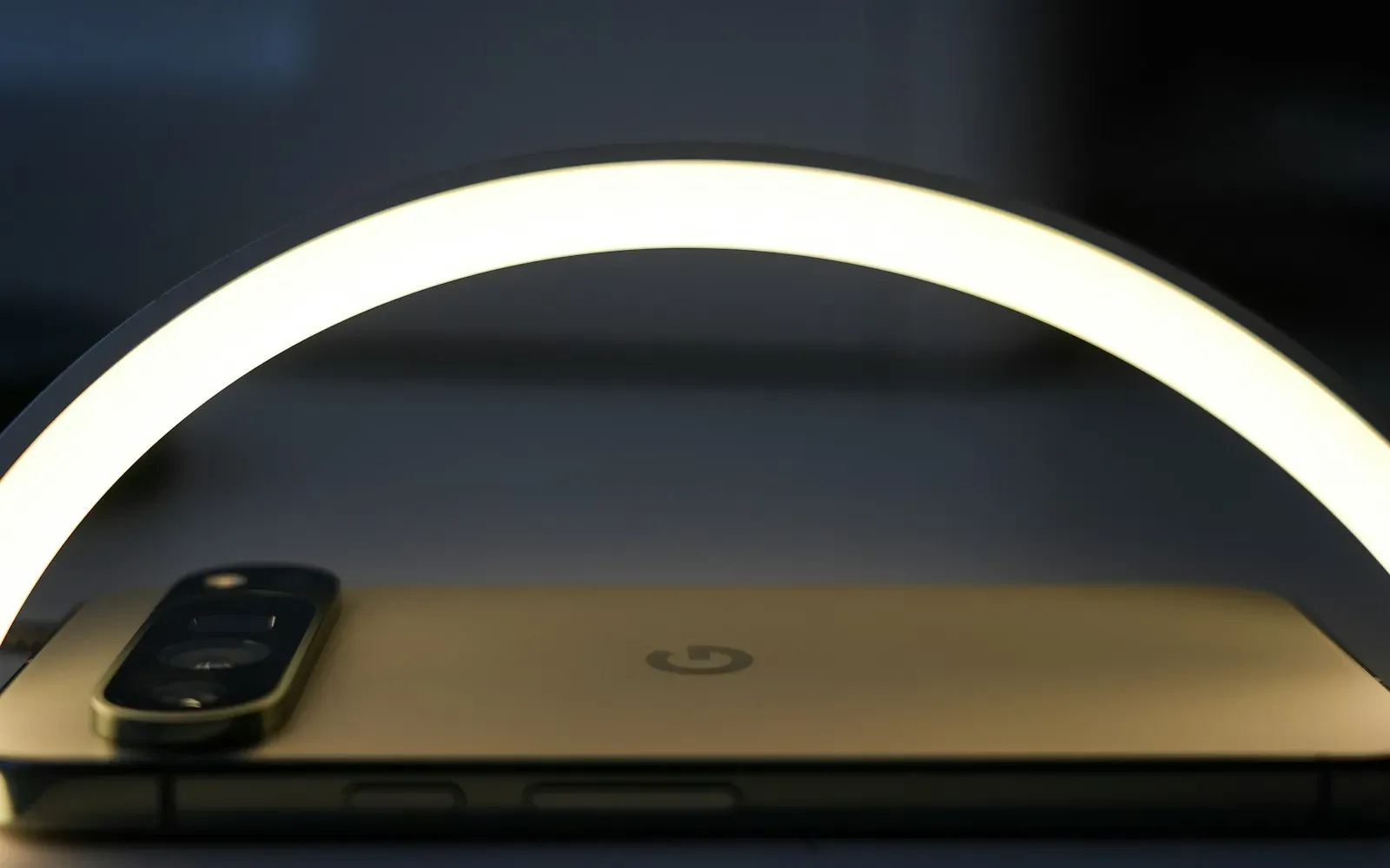 Bogenförmige LED-Leuchte strahlt warmes Licht über ein Smartphone auf dem Tisch