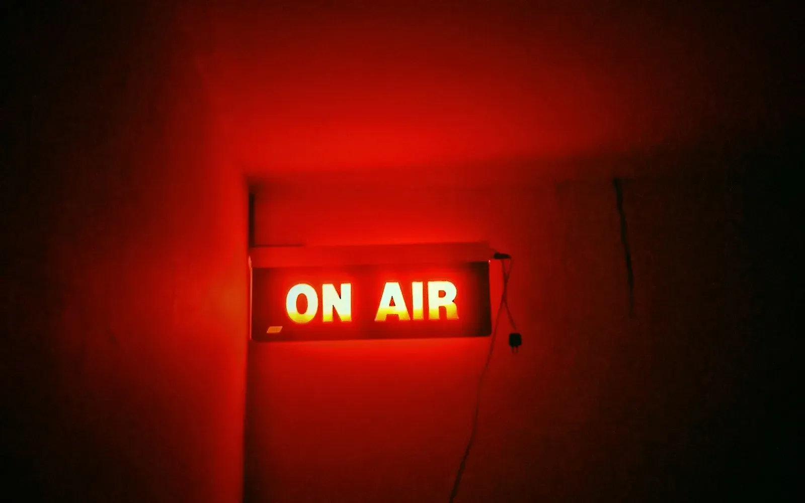 Rot leuchtendes On-Air-Schild an einer dunklen Wand – Chaturbate, Stripchat und BongaCams im Vergleich