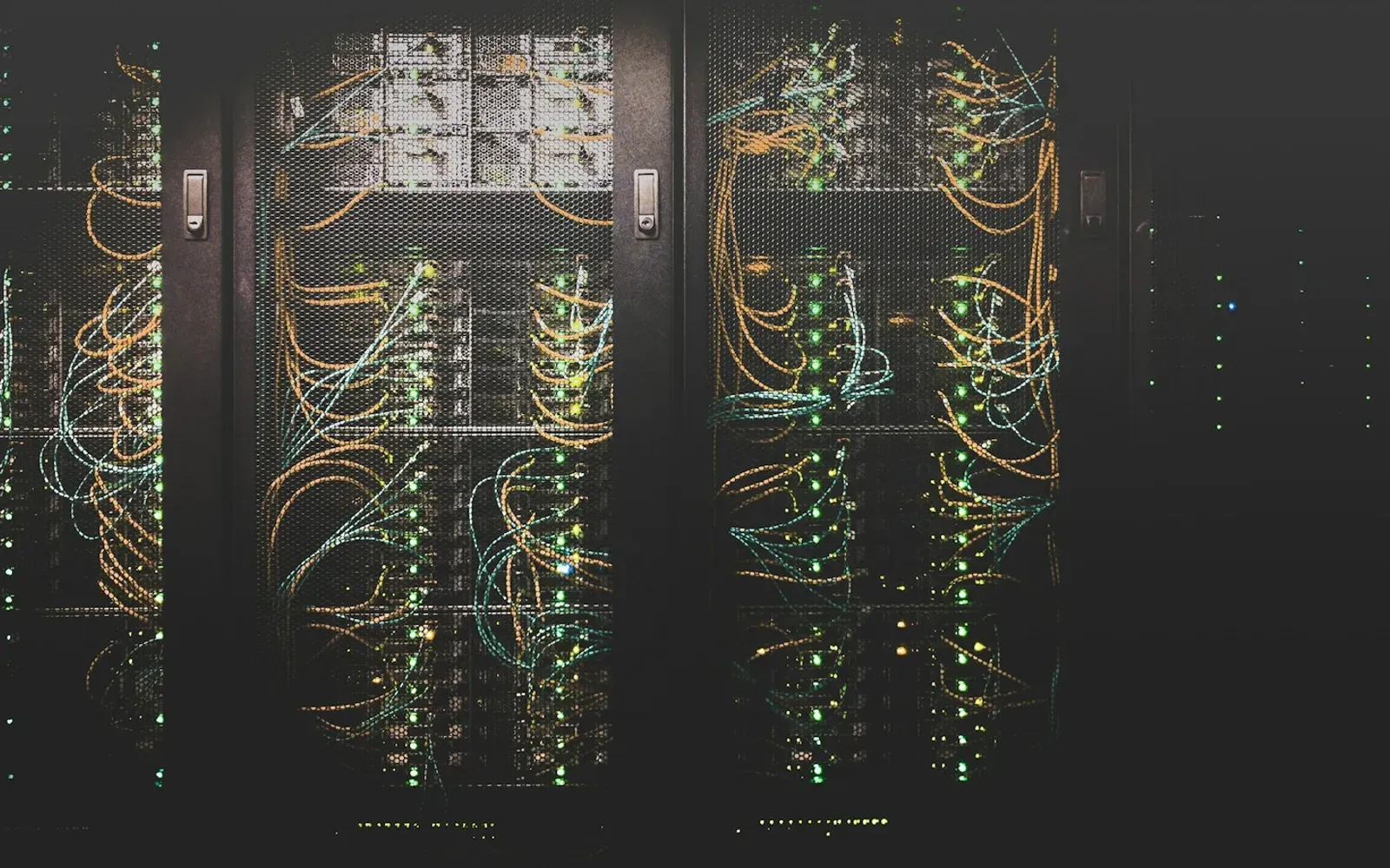 Serverschränke mit bunten Netzwerkkabeln in einem dunklen Rechenzentrum – was ist Erome und wo liegen die Daten