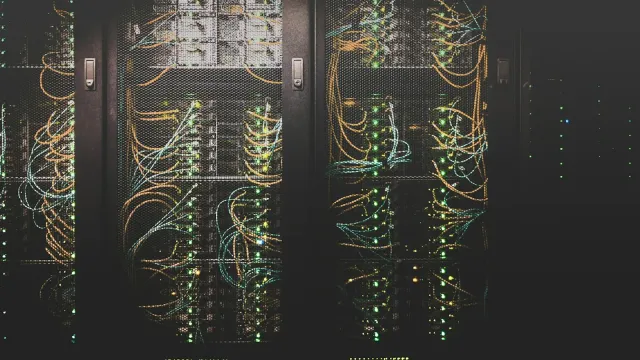 Serverschränke mit bunten Netzwerkkabeln in einem dunklen Rechenzentrum – was ist Erome und wo liegen die Daten